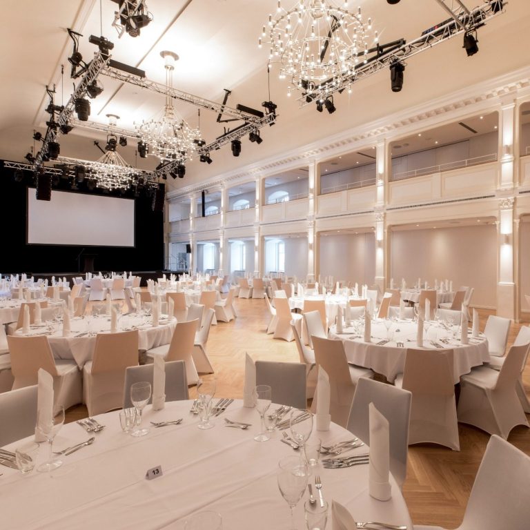 Großer Saal in Reihenbestuhlung Der leere große Saal in Reihenbestuhlung mit aufgebauter Bühne und blauer Bühnenbeleuchtung.